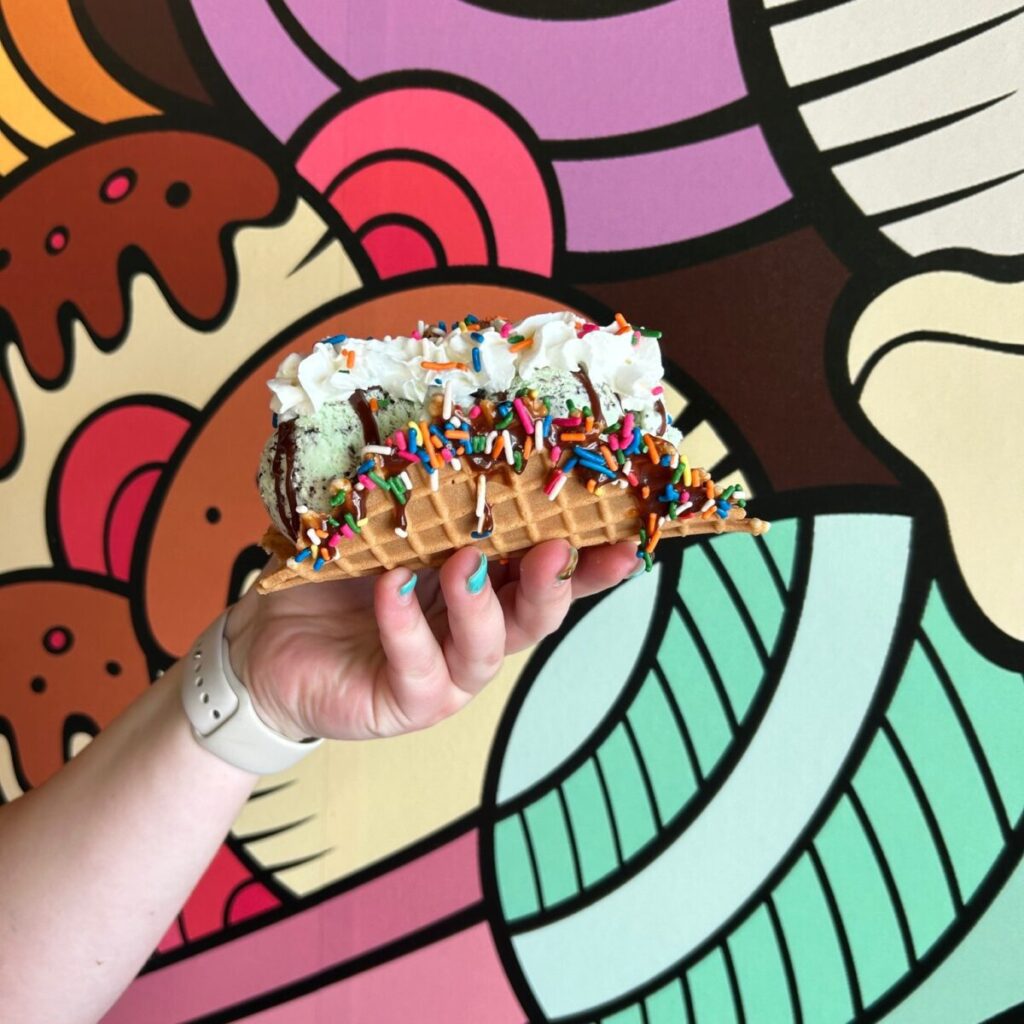 Woman's hand holding up ice cream taco.