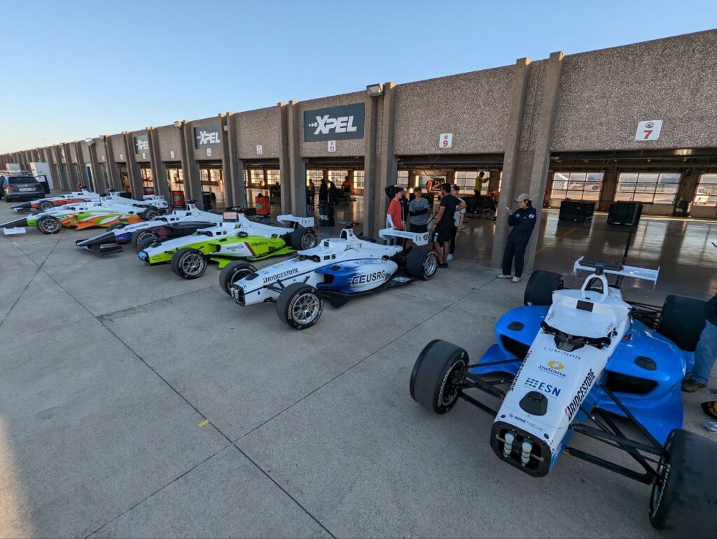 A line of race cars outside a building.