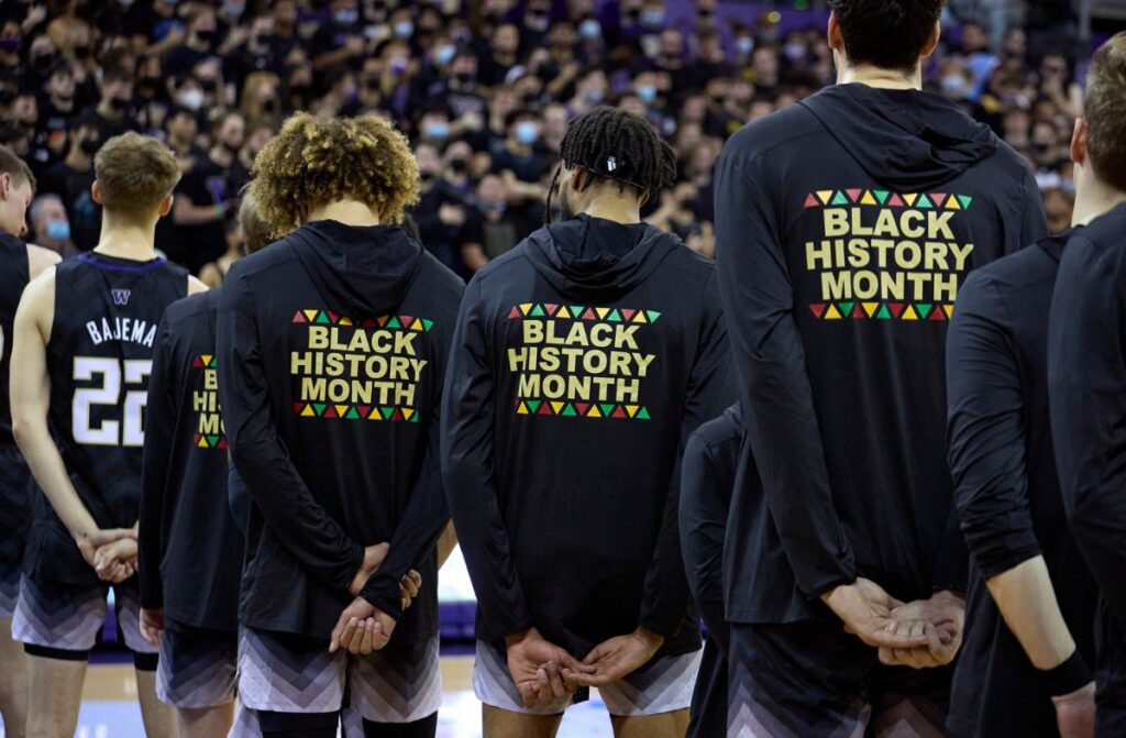 FILE - Washington players stand during the playing of the national anthem wearing warm-up jackets for Black History Month before an NCAA college basketball game against Arizona, Feb. 12, 2022, in Seattle.